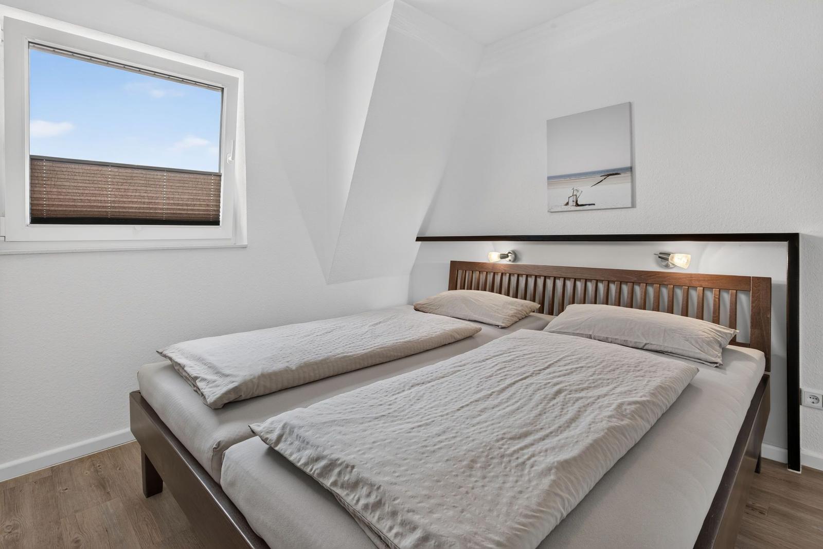 Schlafzimmer mit Doppelbett, Fenster und Wandbild.