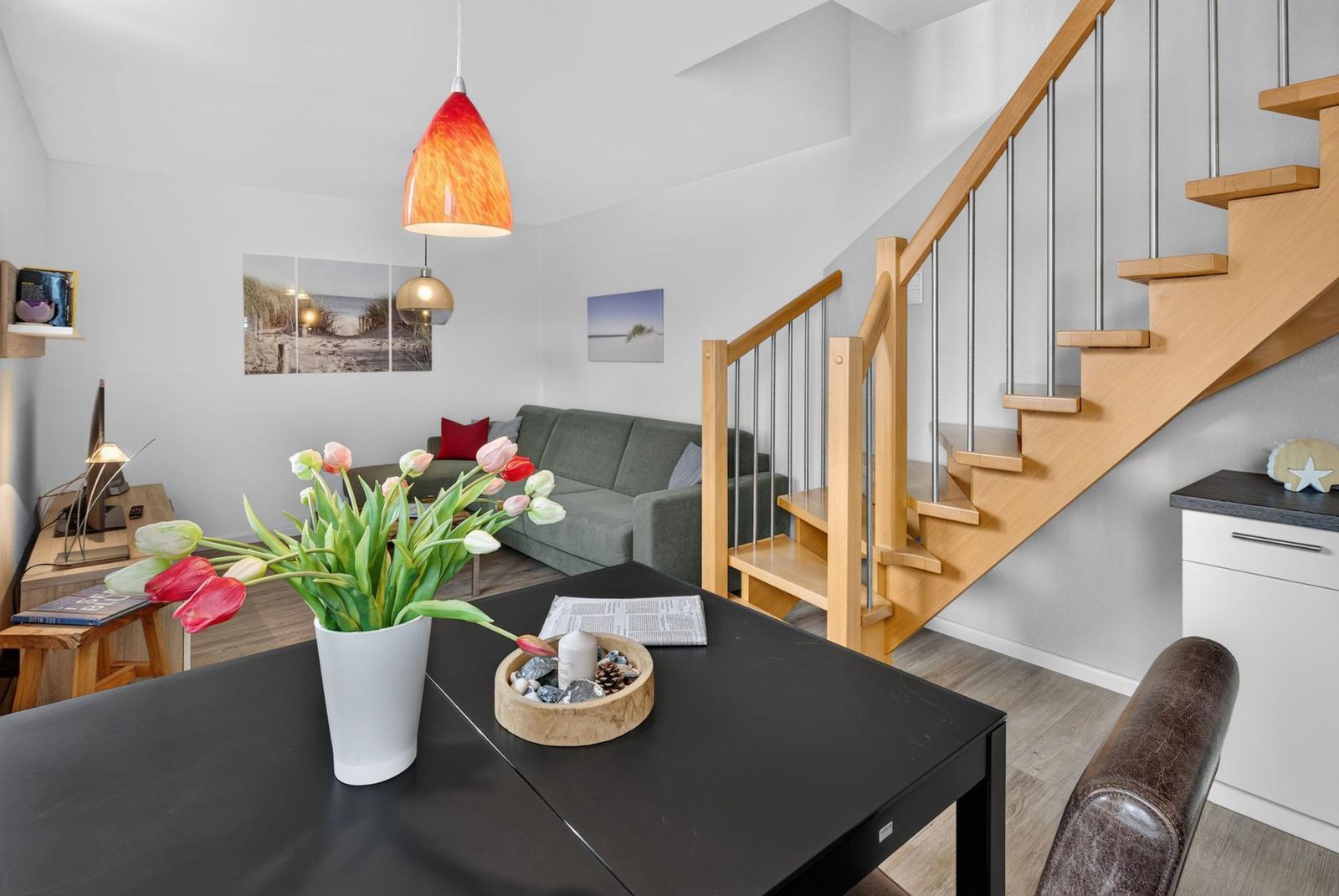 Eingangsbereich mit Treppe, Esstisch und Wohnzimmer im Hintergrund.