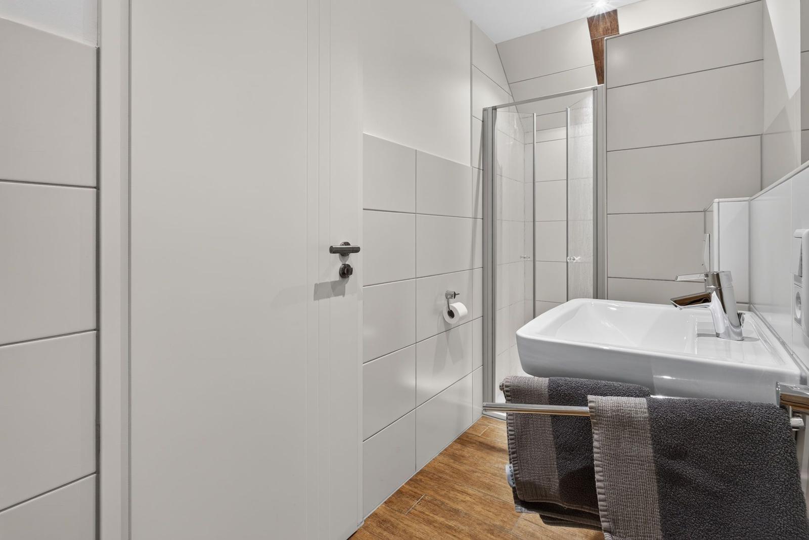 Badezimmer mit Dusche, Waschbecken und Handtuchhalter