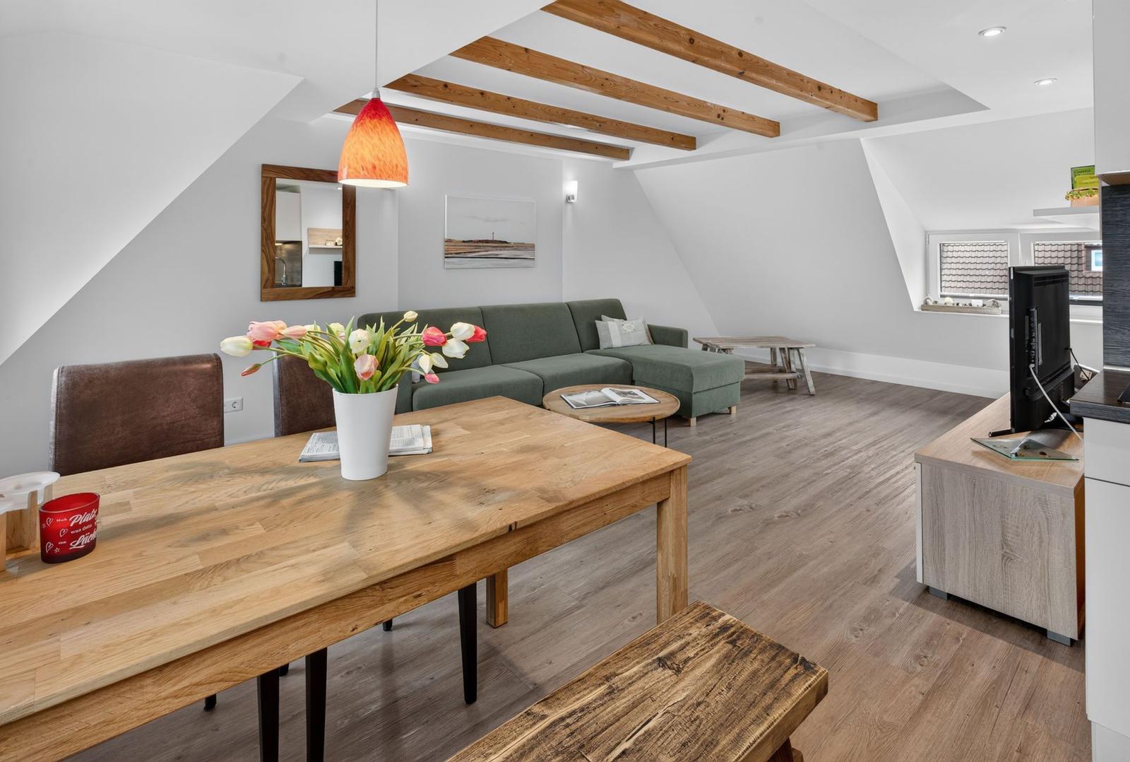 Wohn- und Essbereich mit Holztisch, Sofa und Balkonfenster.