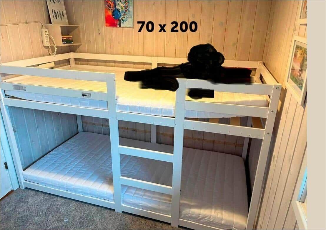 Doppelstockbett mit Matratzen und Kissen. Wand mit Holzverkleidung und Gemälde.