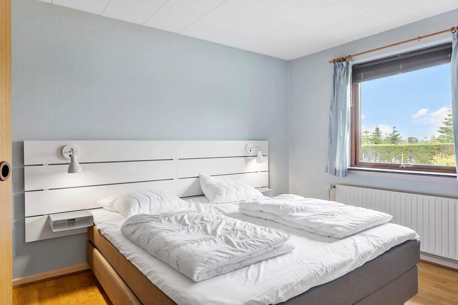 Schlafzimmer mit Doppelbett, Fenster und Holzboden.