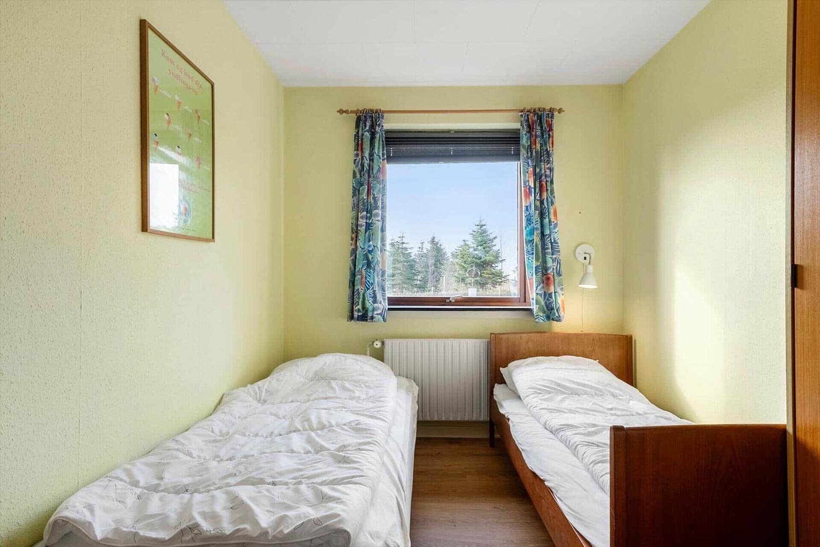 Ein Schlafzimmer mit einem Bett, einem Stuhl und einem Fenster mit Blick auf Bäume.