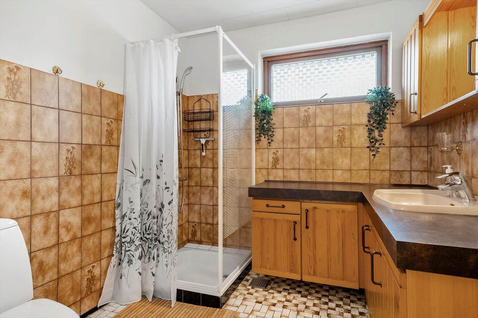 Badezimmer mit Toilette, Waschbecken und Spiegel an orangefarbenen Fliesen.