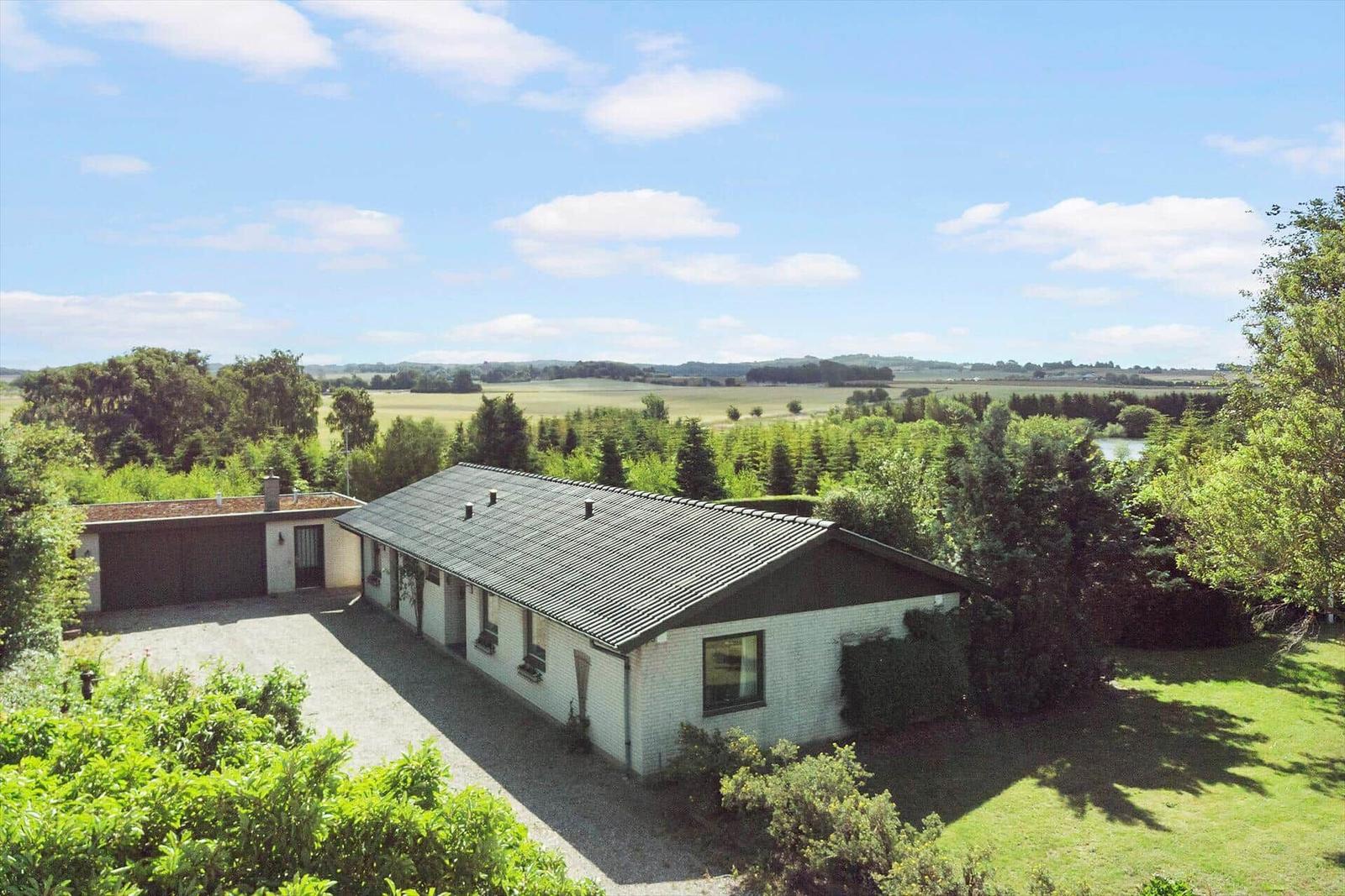 Durch Fensterblick auf Garten mit Skulptur und Waldsee