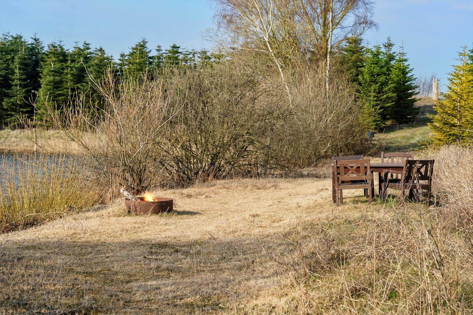 Ein See mit Wald im Hintergrund und Grasland im Vordergrund.