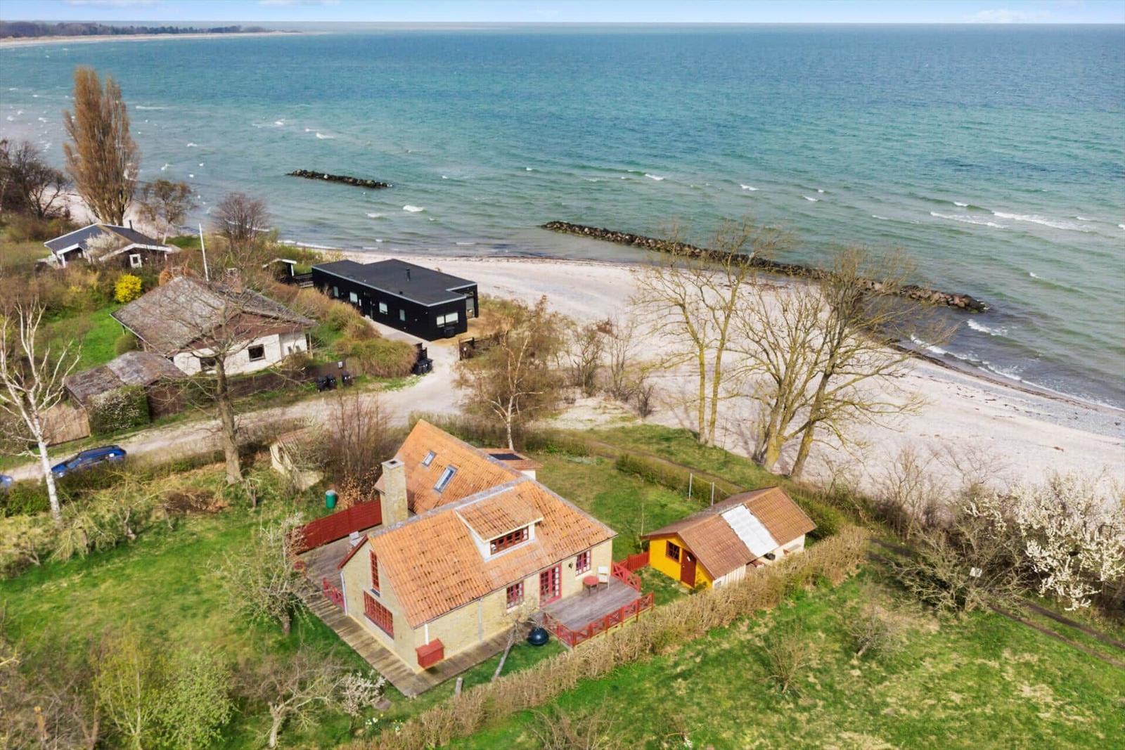 Haus mit rotem Dach und Garten neben Strand und Meer.