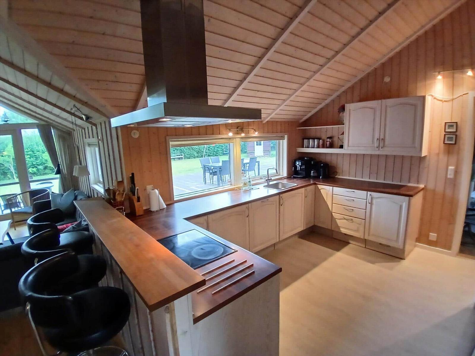 Wohn- und Essbereich mit Holzdecke, Sofa, Esstisch und Fernseher.