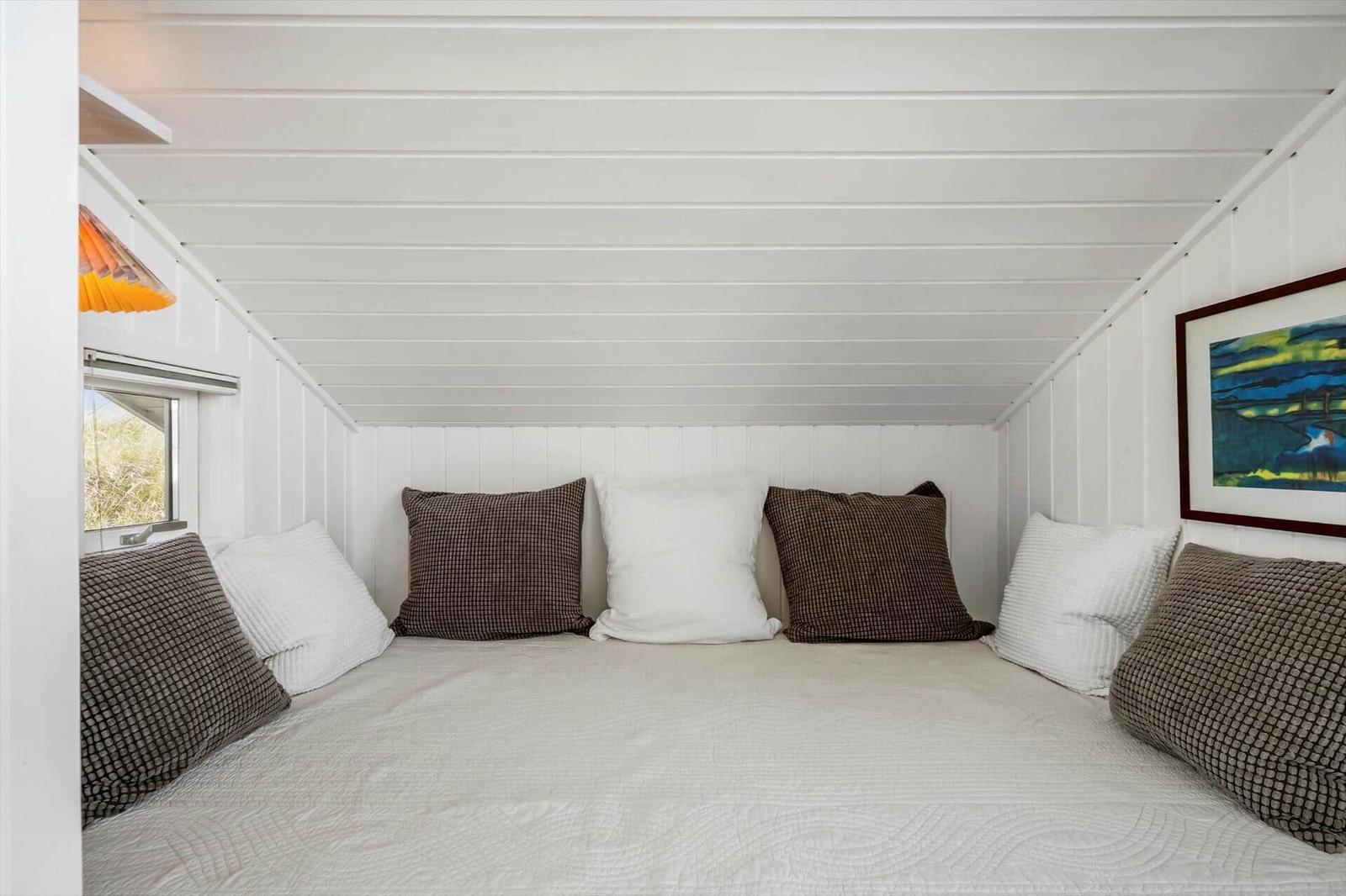 Ein Bett mit Kissen und Decke in einem Raum mit weißen Wänden und Decken.