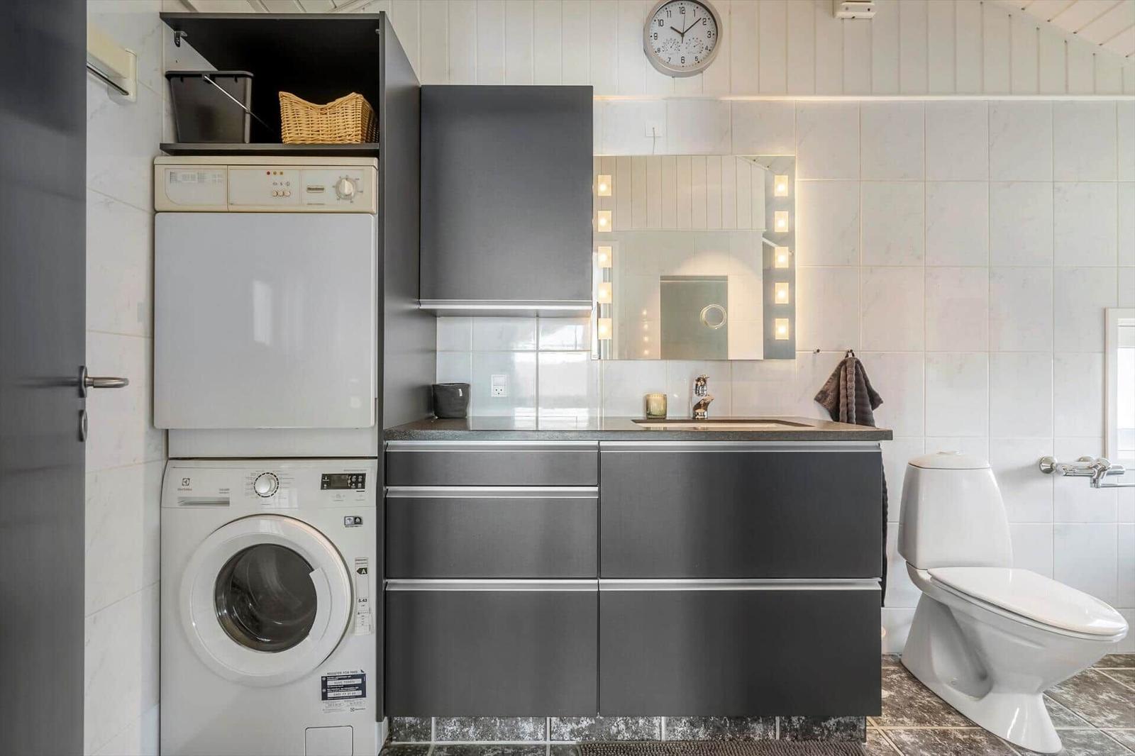 Badezimmer mit Waschmaschine, Spiegelschrank und Toilette.