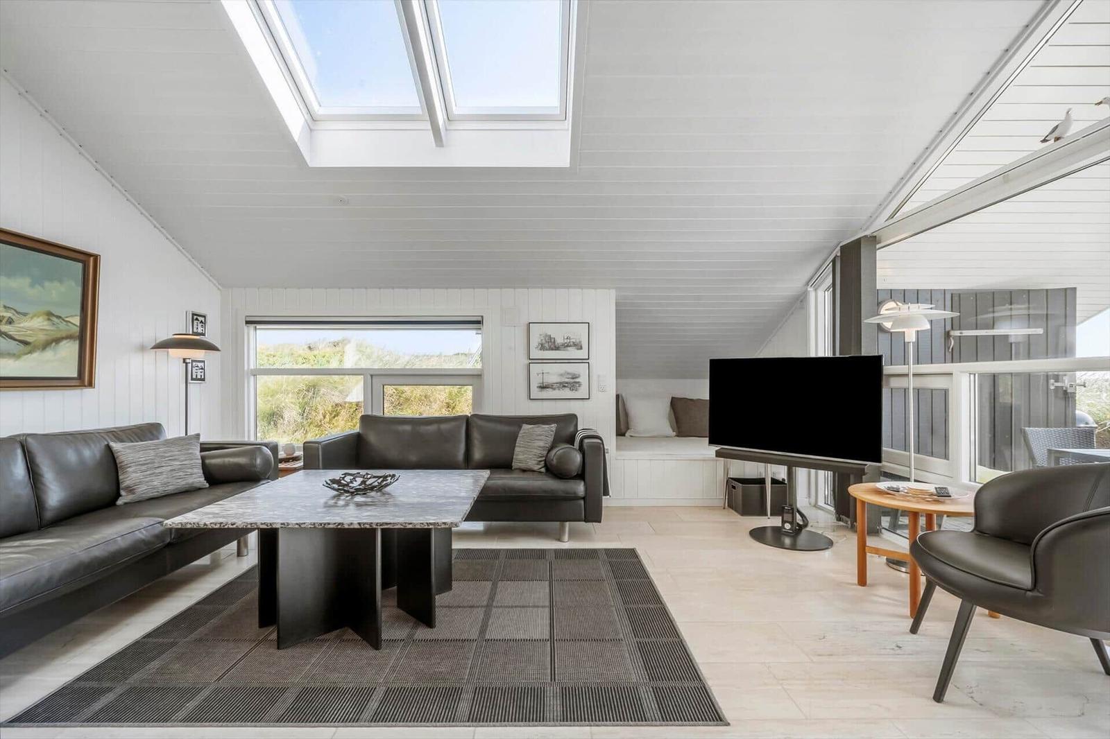 Wohnzimmer mit Ledersofa, TV und Dachfenster. Blick auf Garten.