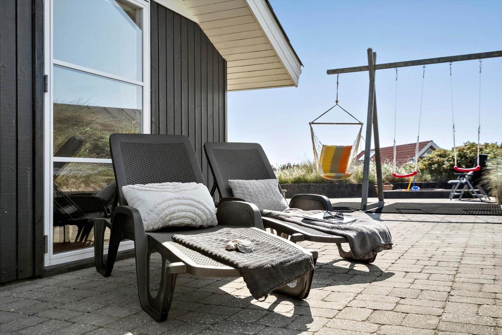 Terrasse mit Liegestühlen, Hängematten und Spielgeräten. Blick auf die Umgebung.
