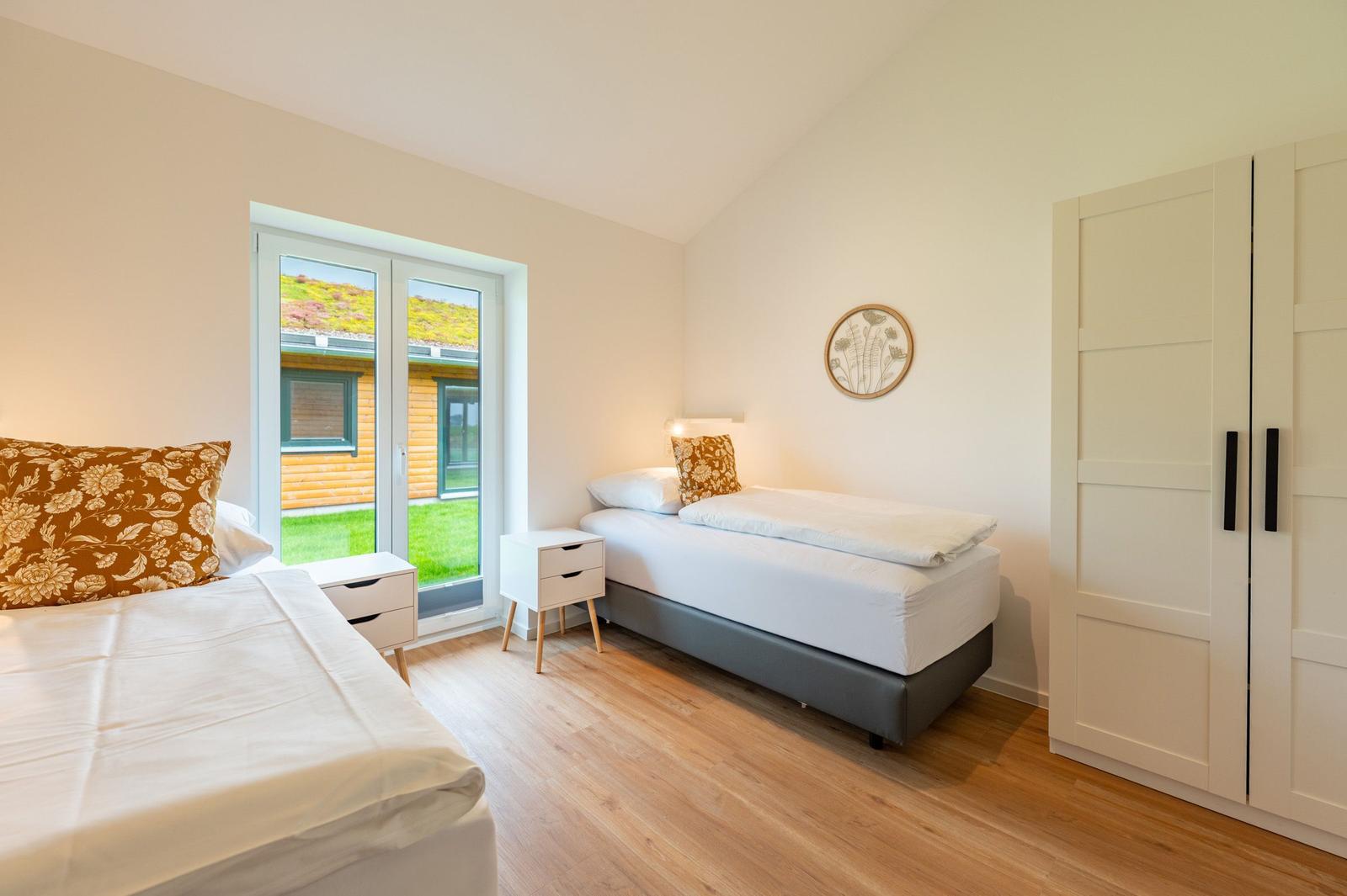 Zwei Betten, Kleiderschrank und Fenster mit Blick auf Garten