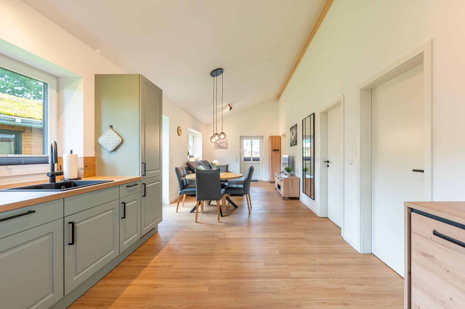 Küche mit Essbereich und Wohnzimmer im offenen Grundriss mit Holzboden und hohem Dach.