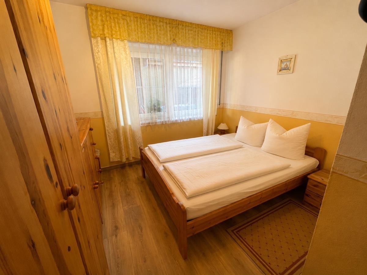 Ein Schlafzimmer mit Holzbett, Gardinen und Schrank.