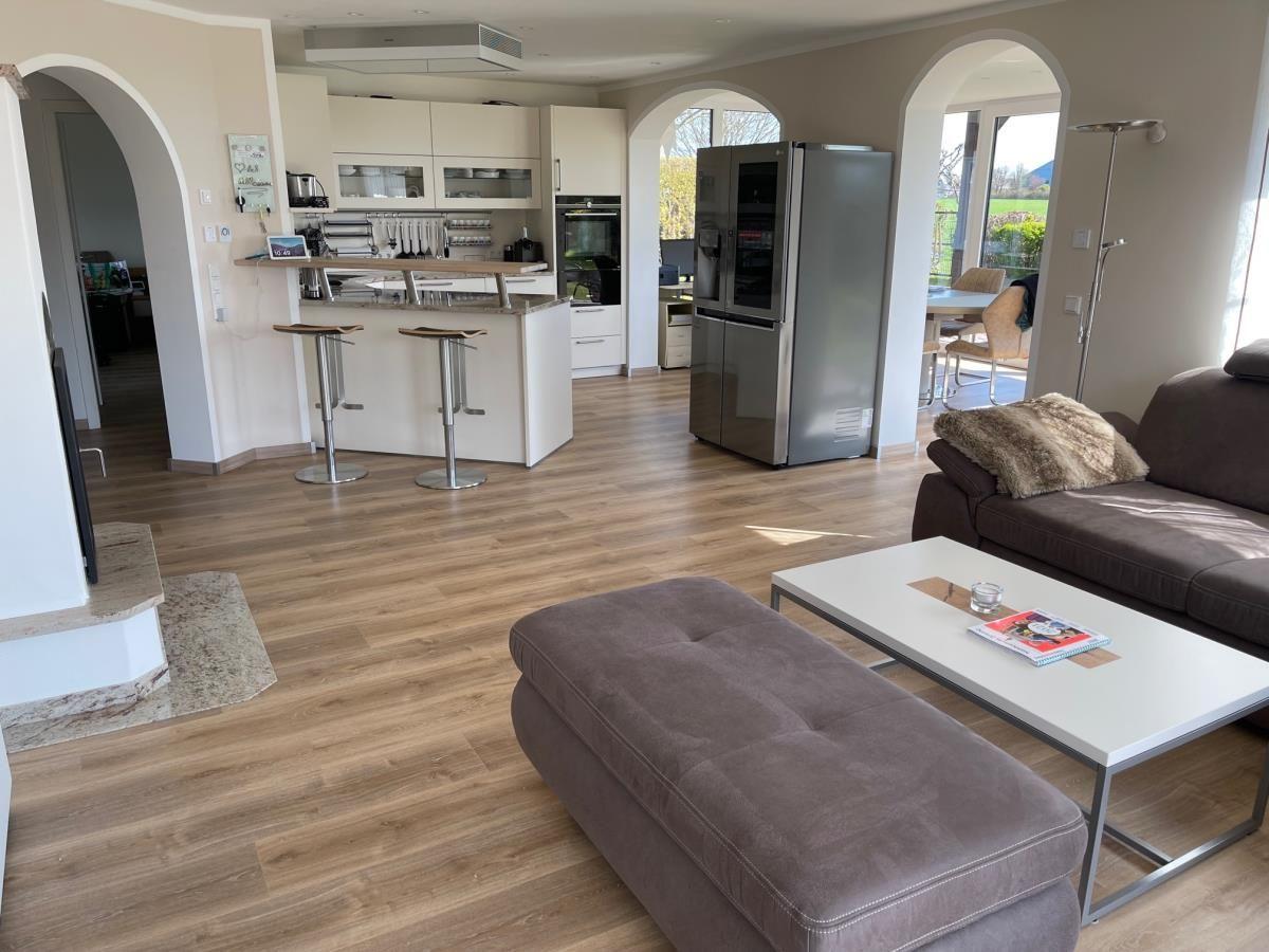 Wohn- und Küchenbereich mit Sofa, Couchtisch und Kühlschrank.