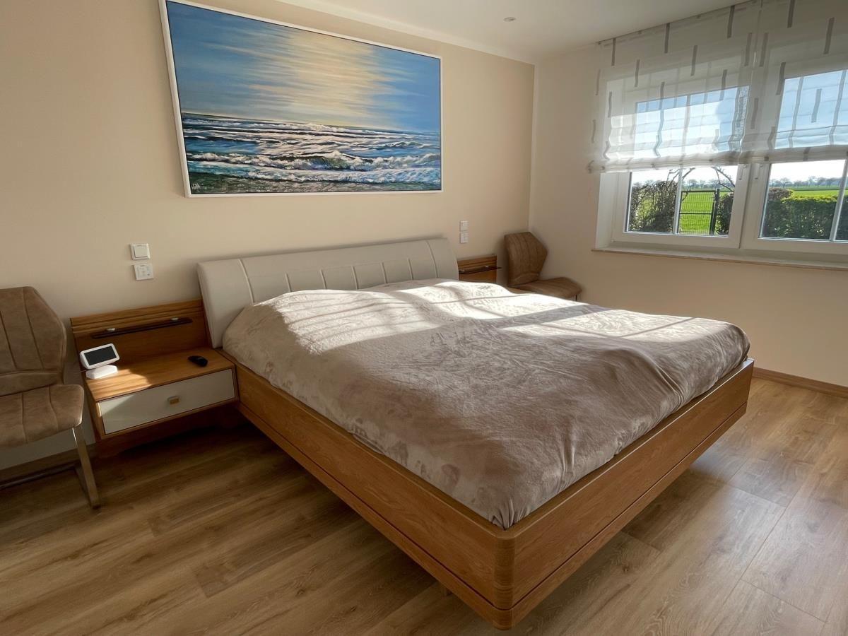 Schlafzimmer mit Doppelbett, Holzboden und Wandbild mit Meeresmotiv.