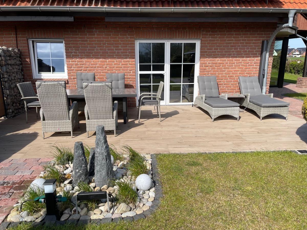 Terrasse mit Sitzgruppe, Liegen und Garten. Roter Backsteinbau mit Glastüren.