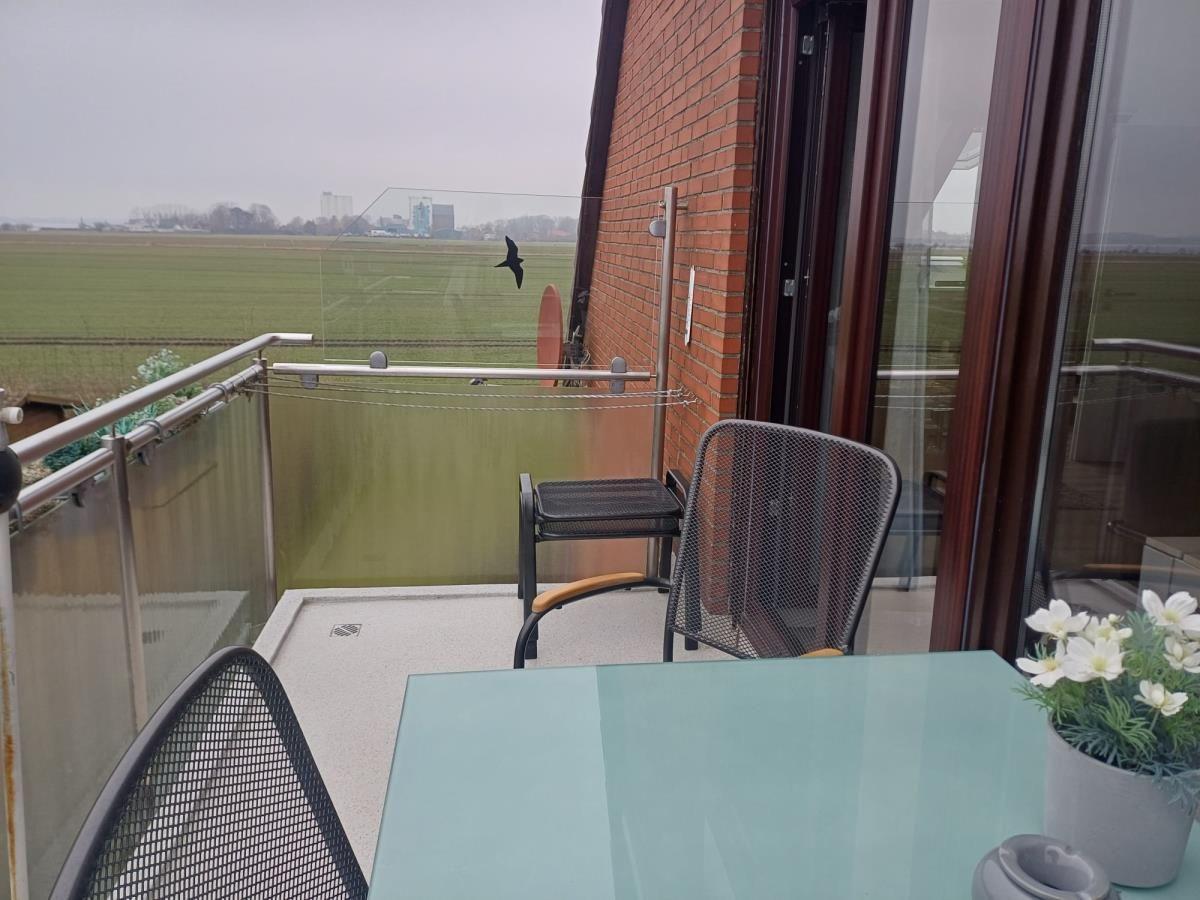 Terrasse mit Tisch und Stühlen, Blick auf Felder und Gebäude