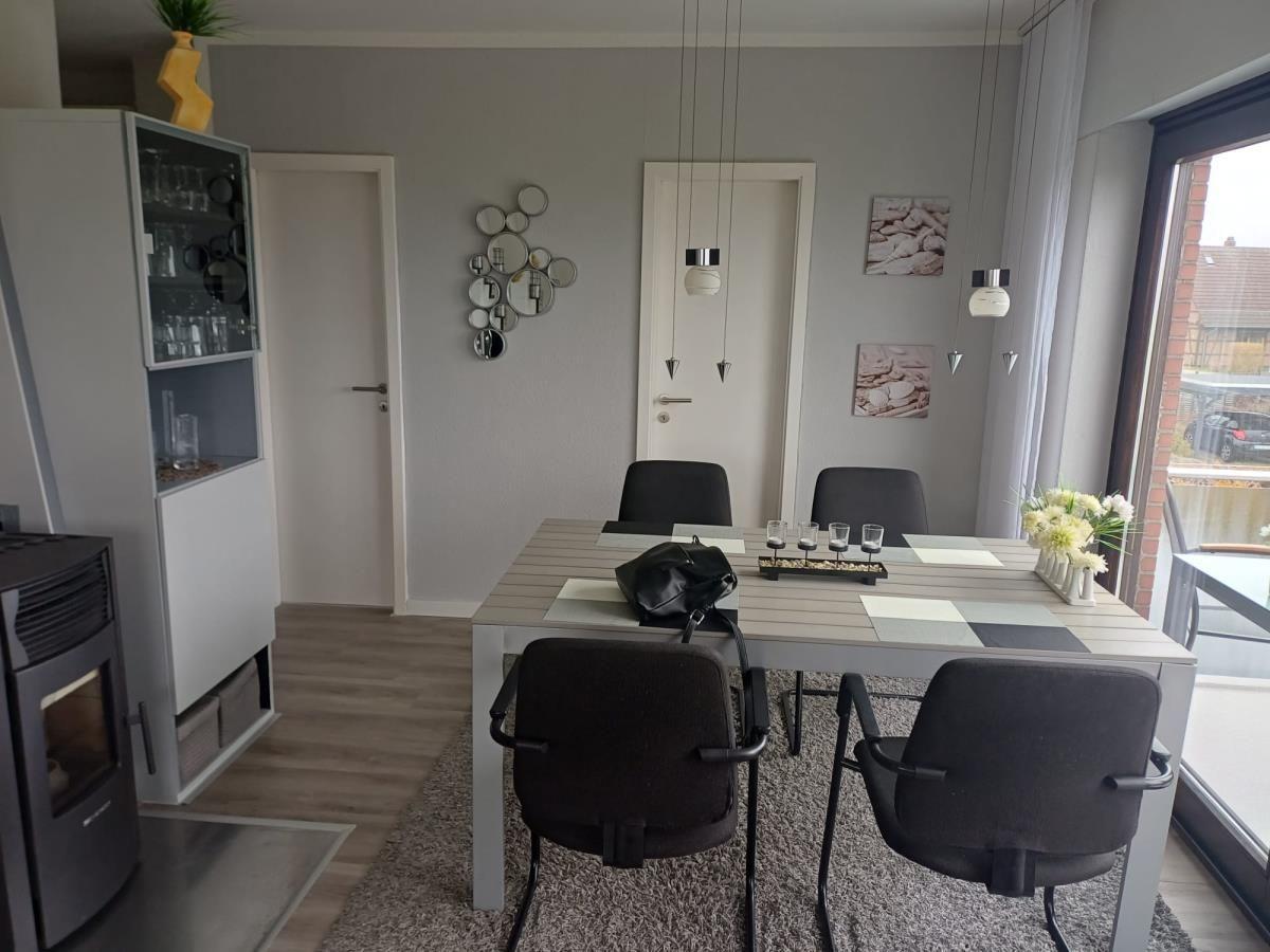 Essbereich mit Tisch, Stühlen und Fenster. Hintergrund: Wanddekoration und Tür.