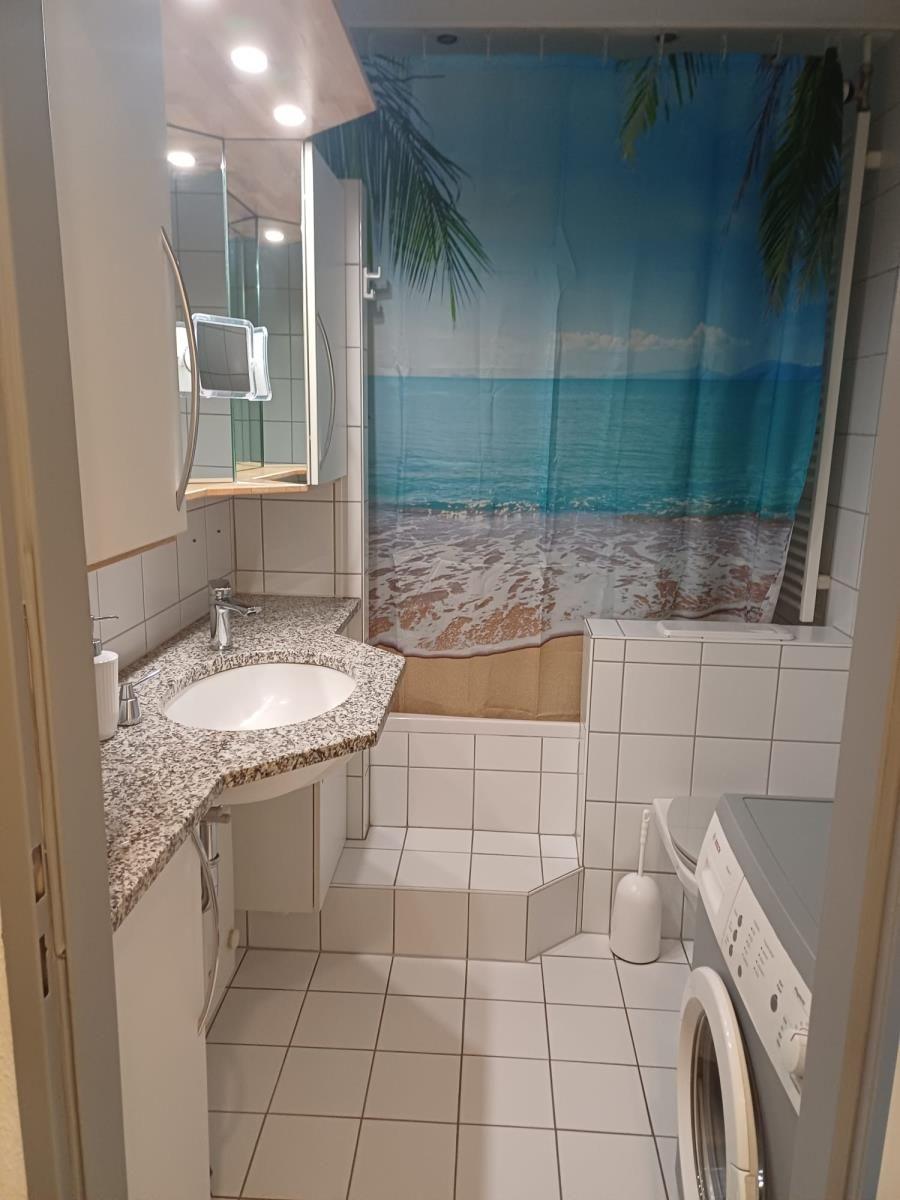 Badezimmer mit Dusche, Waschbecken und Waschmaschine