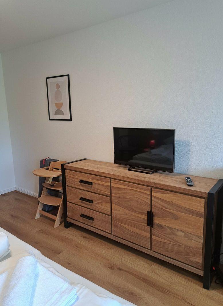 Schlafzimmer mit Holzschrank, Fernseher und Kinderstuhl.