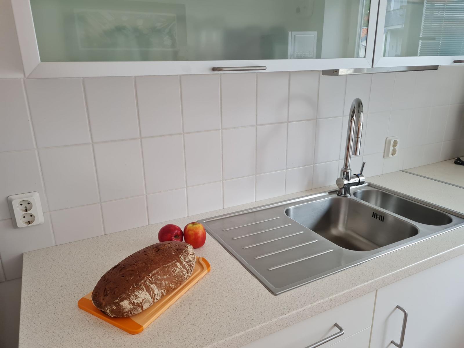 Küche mit Edelstahlspüle, Arbeitsplatte und Brot sowie Äpfeln.
