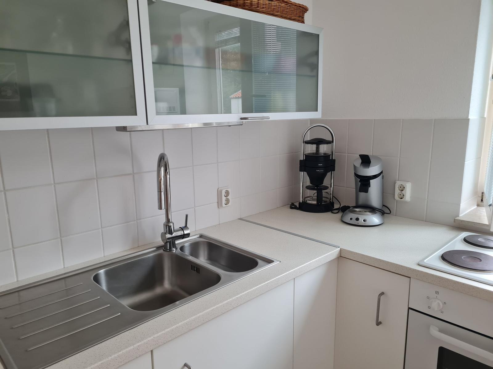 Küche mit Spüle, Kaffeemaschine und Herd