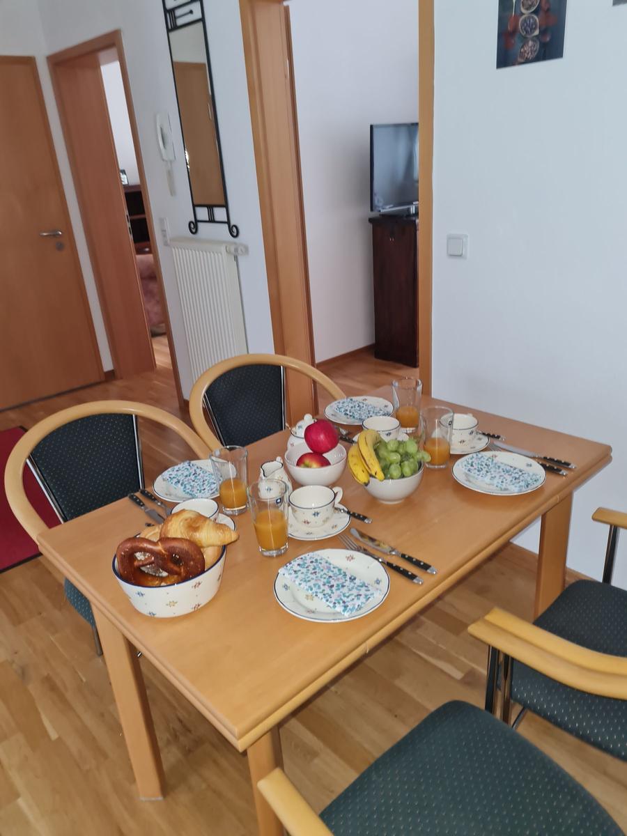 Esstisch mit Frühstückszubehör und Obst auf Holzboden.