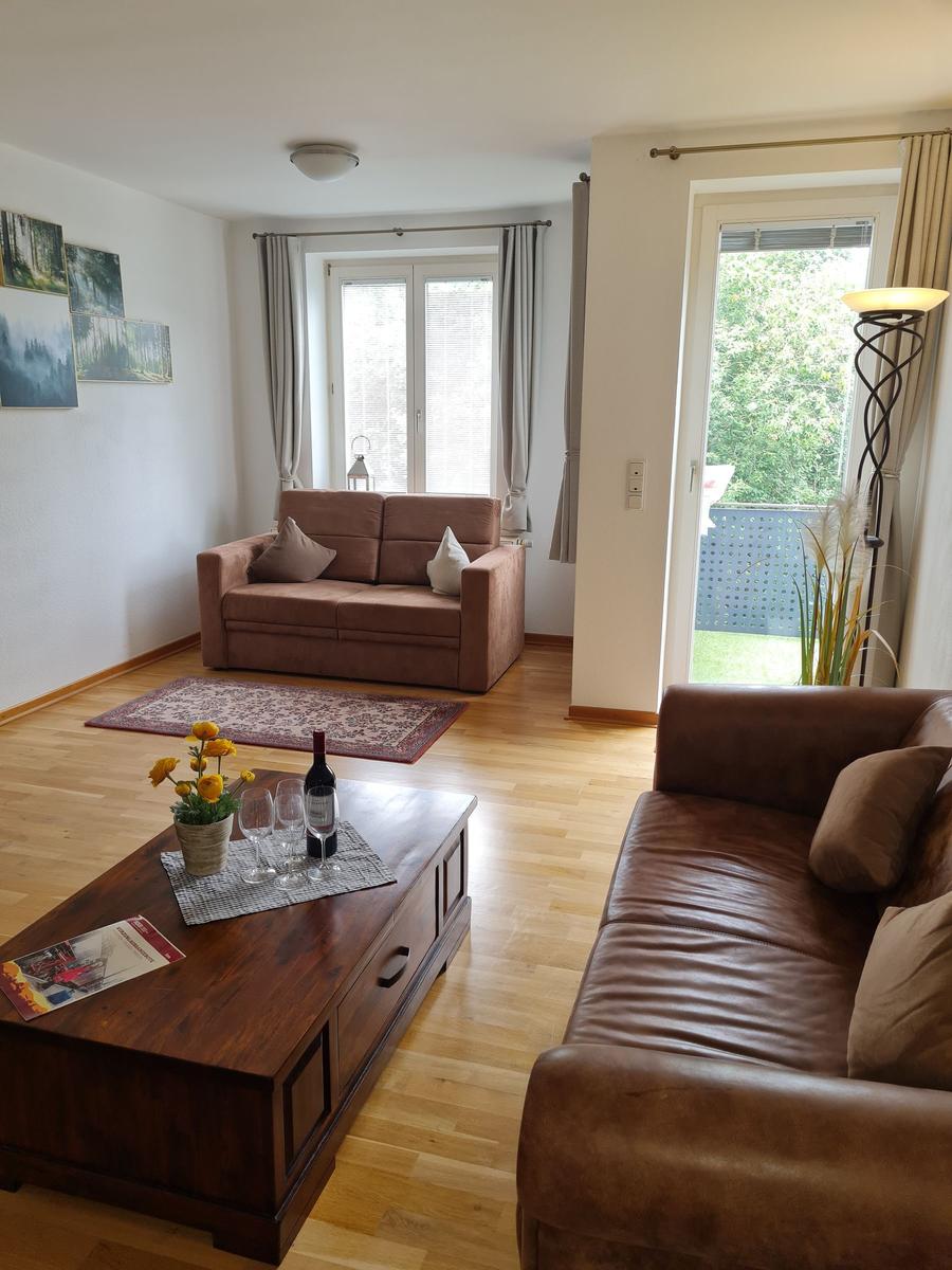 Wohnzimmer mit braunen Sofas, Holzboden und Blick auf Balkon