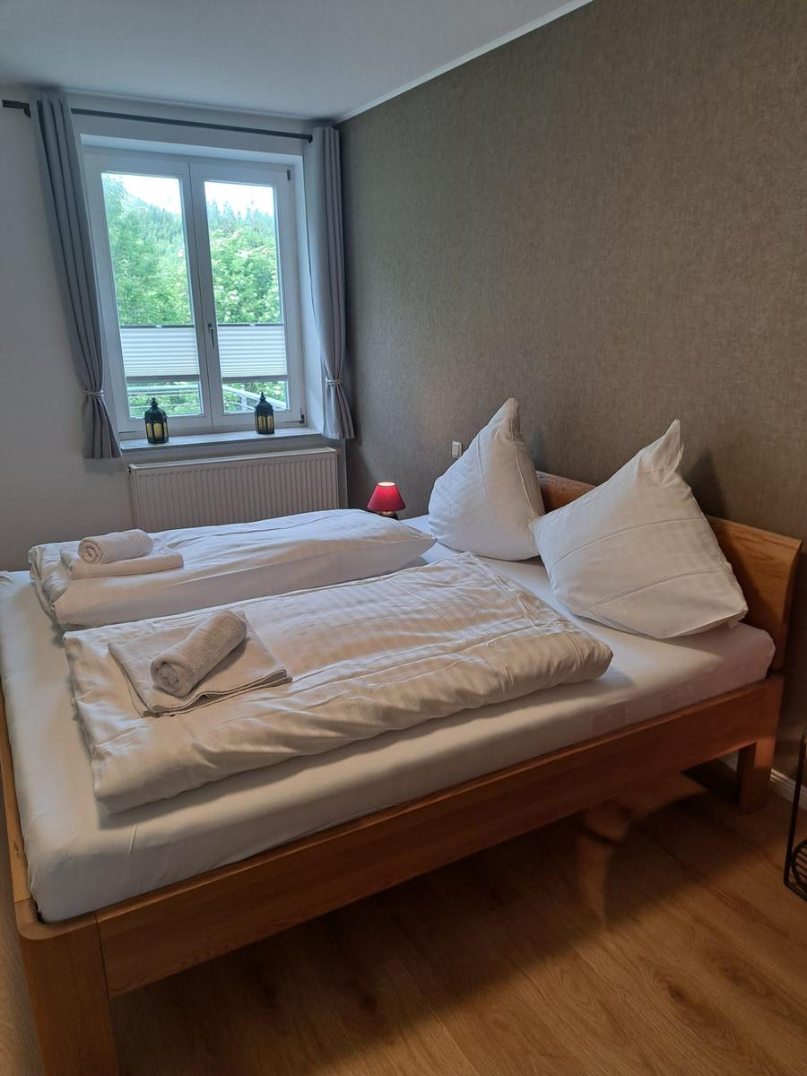 Schlafzimmer mit Doppelbett, Fenster und Holzboden.