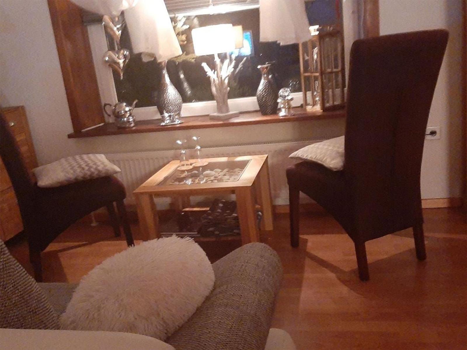 Zwei Stühle und ein Couchtisch vor einem Fenster mit Dekorationsgegenständen.