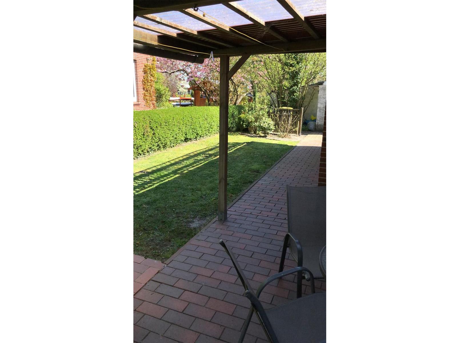 Terrasse mit Sonnenschutz, Garten und Rasenfläche