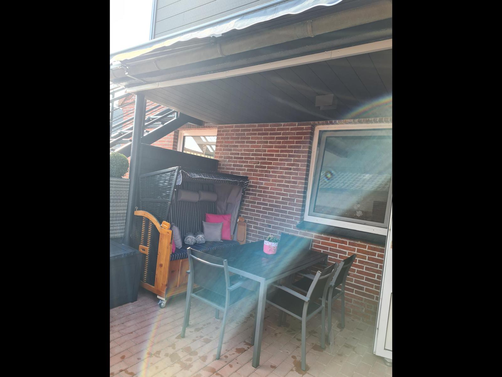 Terrasse mit Tisch, Stühlen und Liege unter Dach