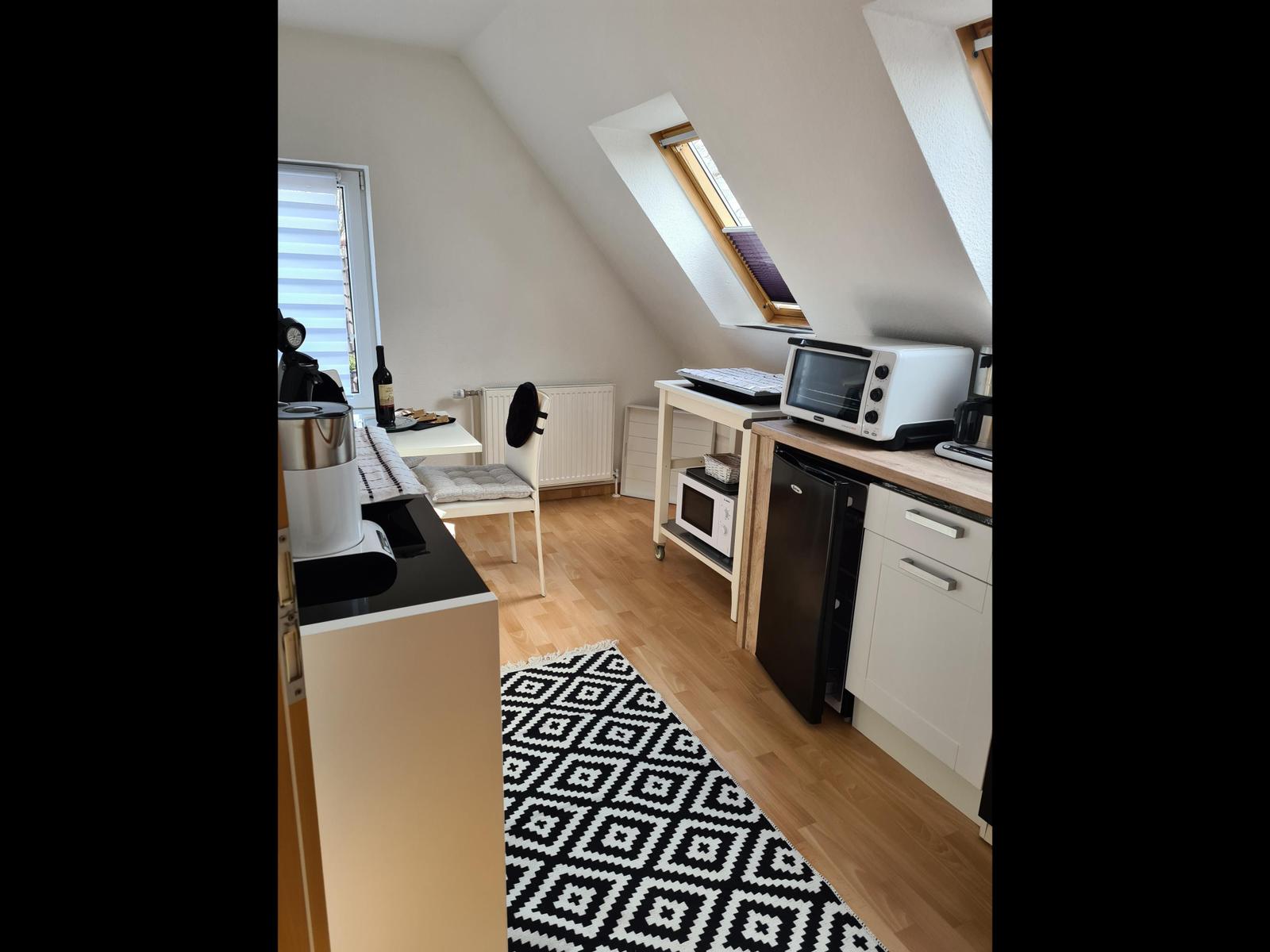 Küche mit Mikrowelle, Kühlschrank und Tisch mit Stuhl.