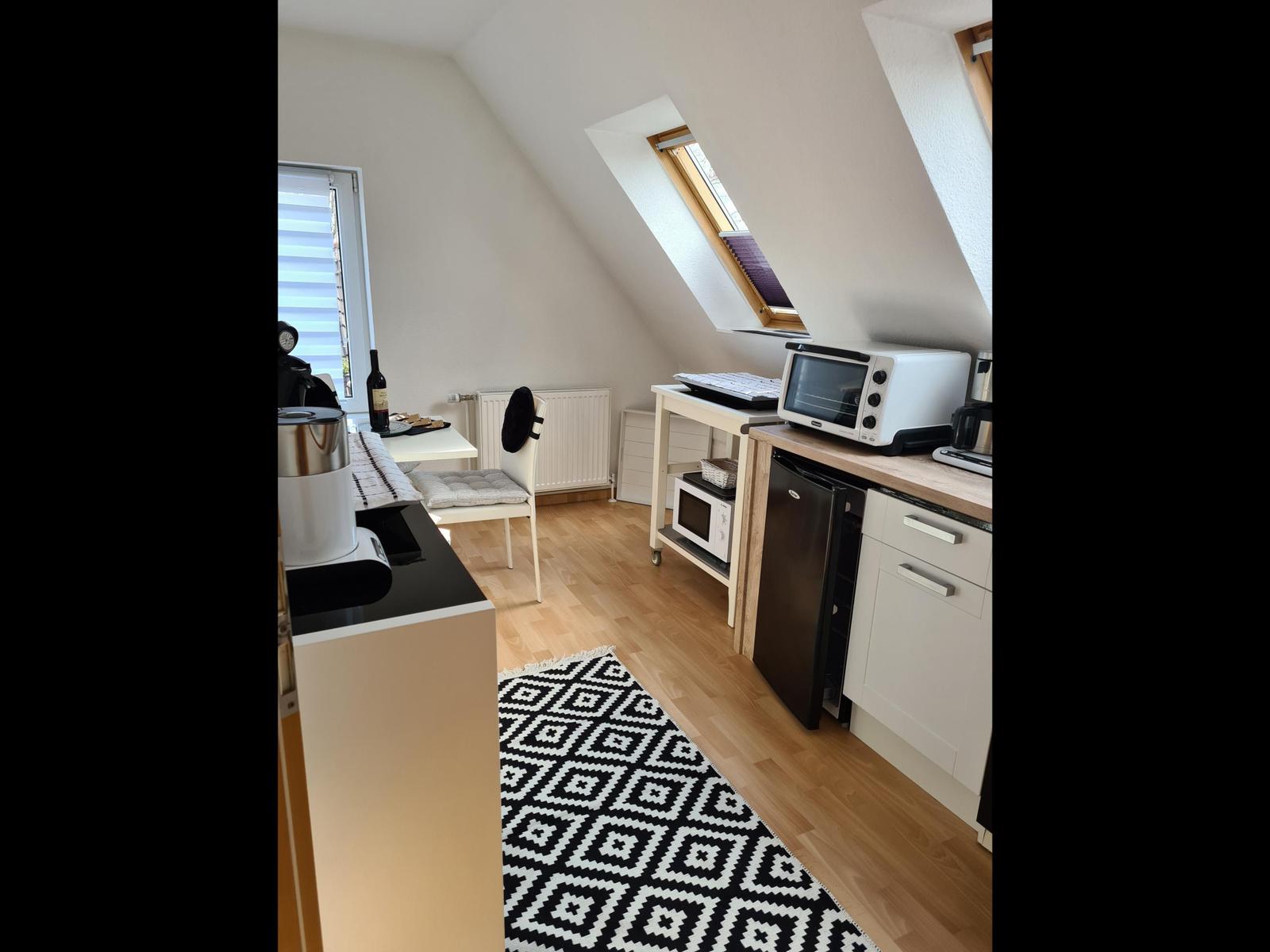 Küche mit Dunstabzug, Kühlschrank und Mikrowelle unter Dachschrägen.