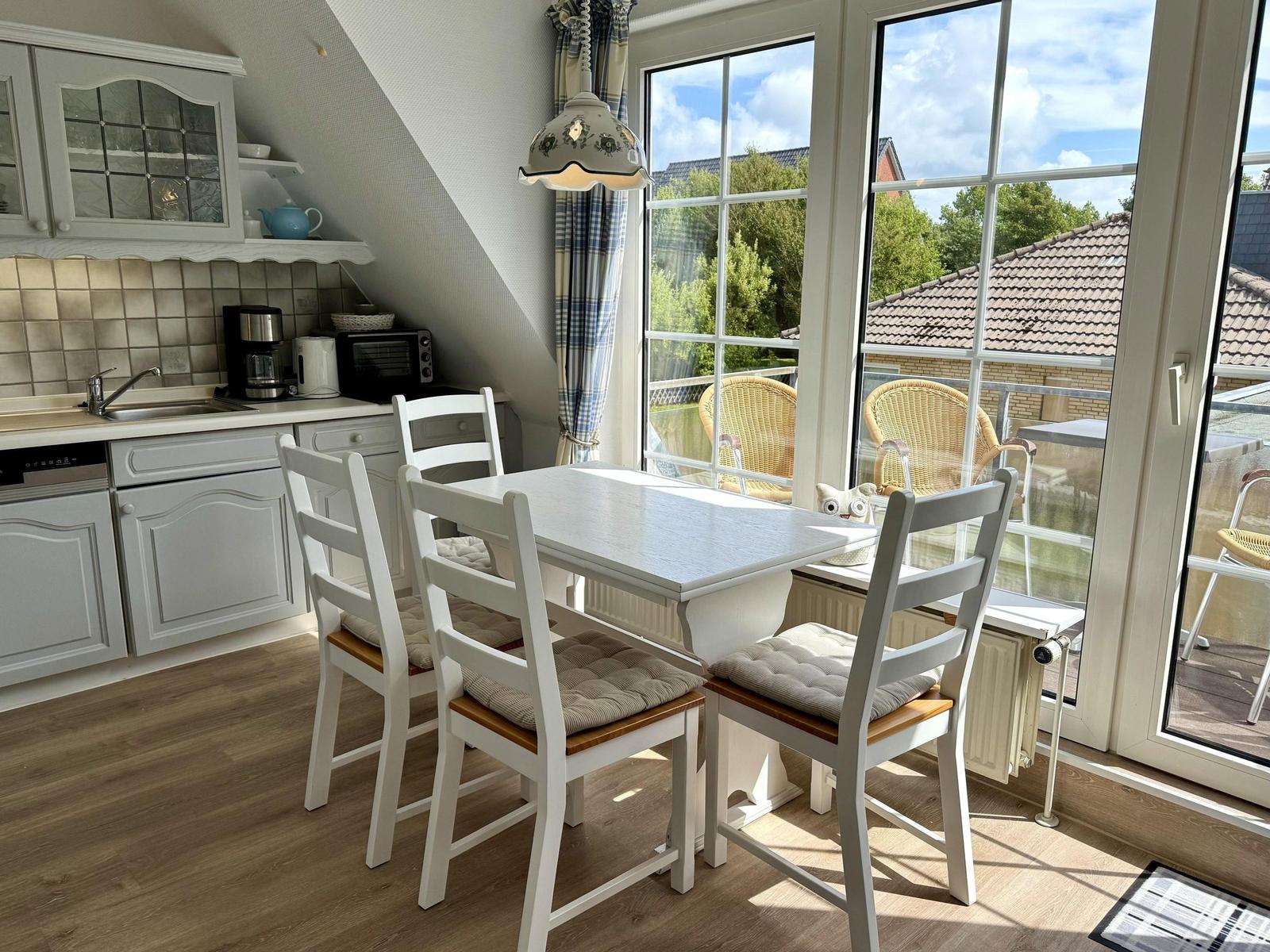 Dining area with white table and chairs, view to balcony with seating.