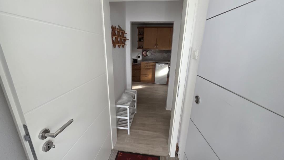 Eingangsbereich mit Blick in die Küche. Holzfußboden und weiße Türen.