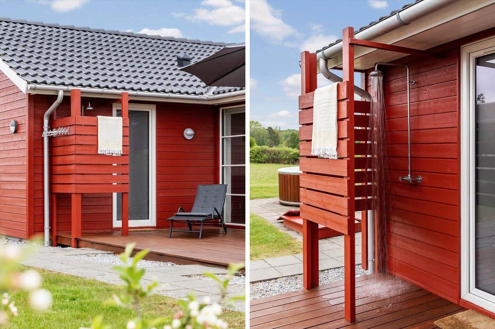 Red wooden outdoor area with shower and lounge chair. Background: grass and forest.