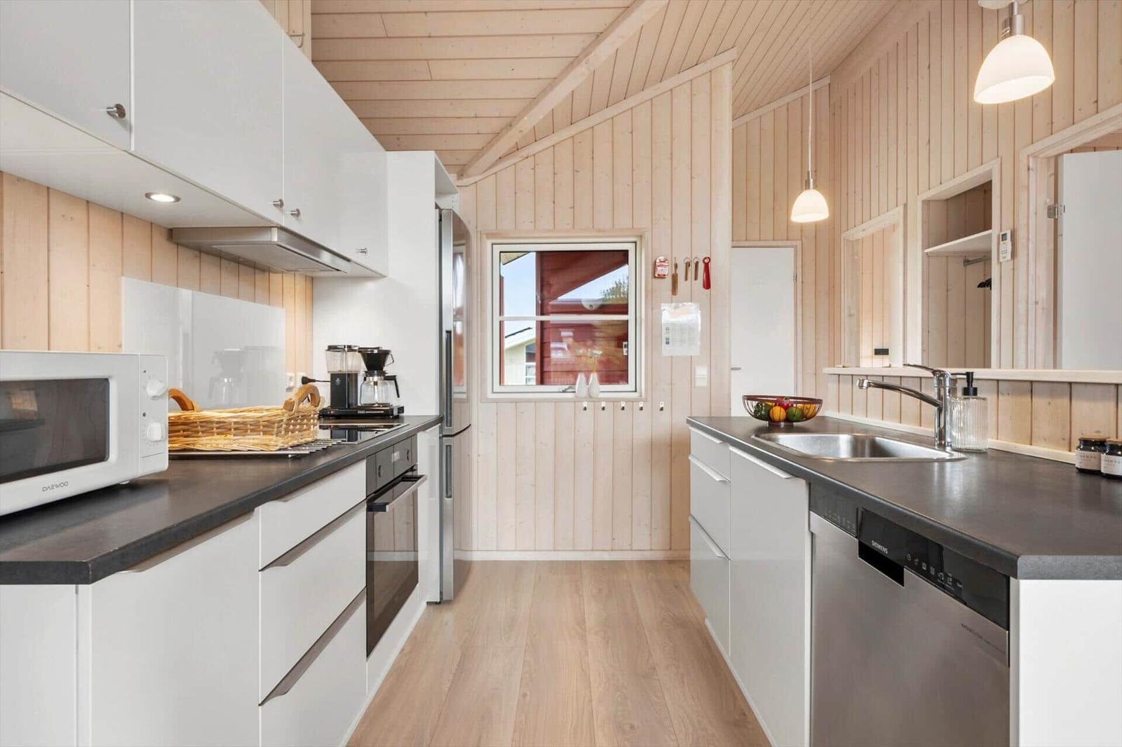 Kitchen with white cabinets, dark countertops, and wooden walls.