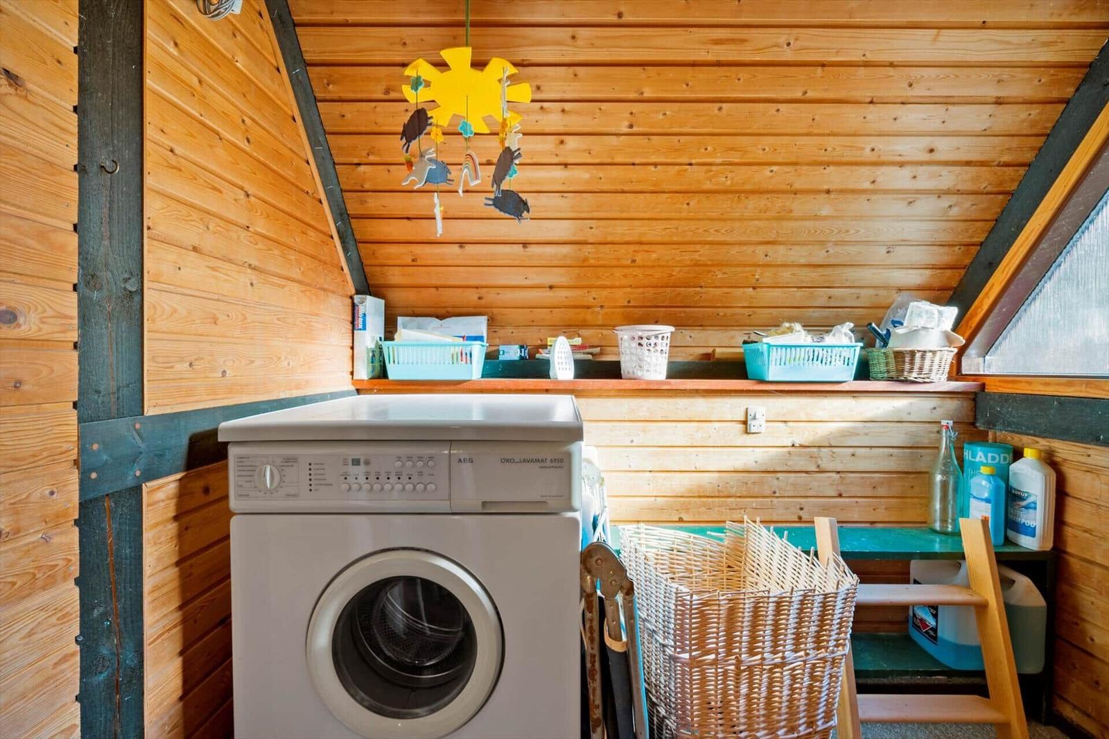 Waschmaschine in einem Raum mit Holzwänden und einem Regal mit Körben.