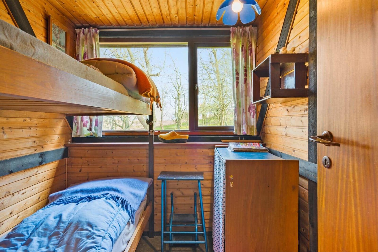 Zimmer mit Doppelstockbett, Fenster und Holzwand