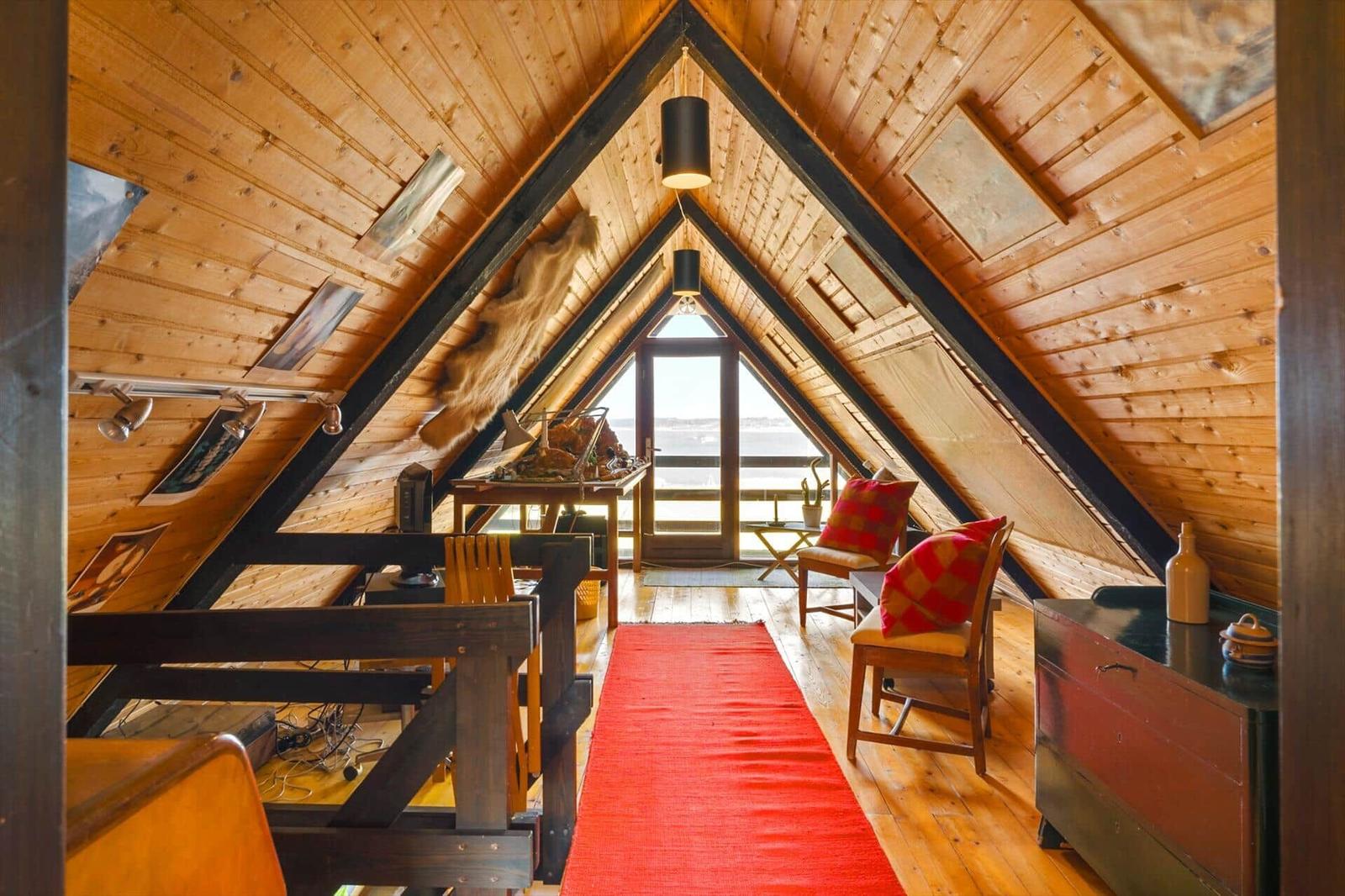 Dachgeschoss mit Holzwand, rotem Teppich und Sitzgelegenheiten