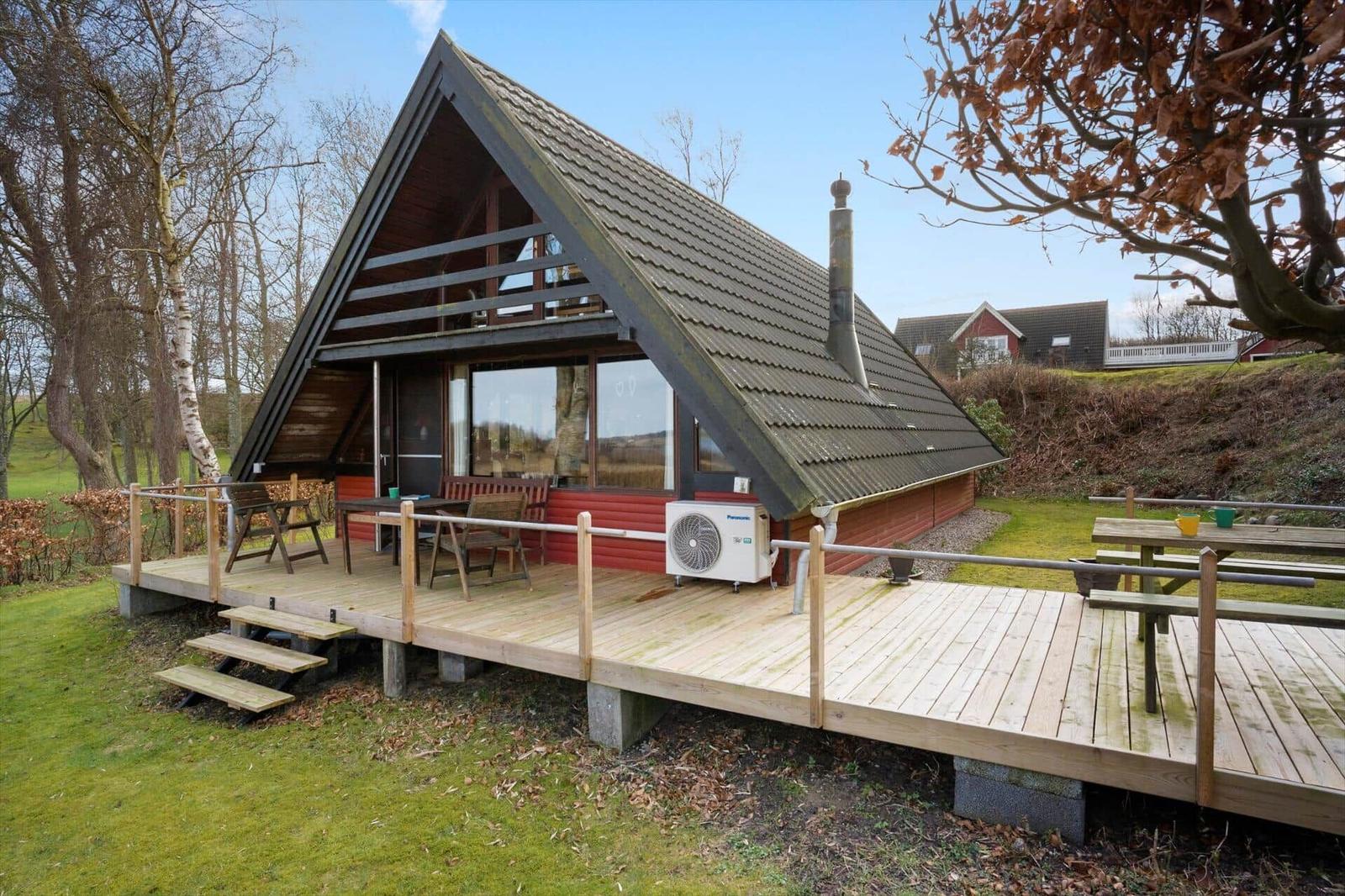 Holzhaus mit Terrasse und Grillplatz im Freien.