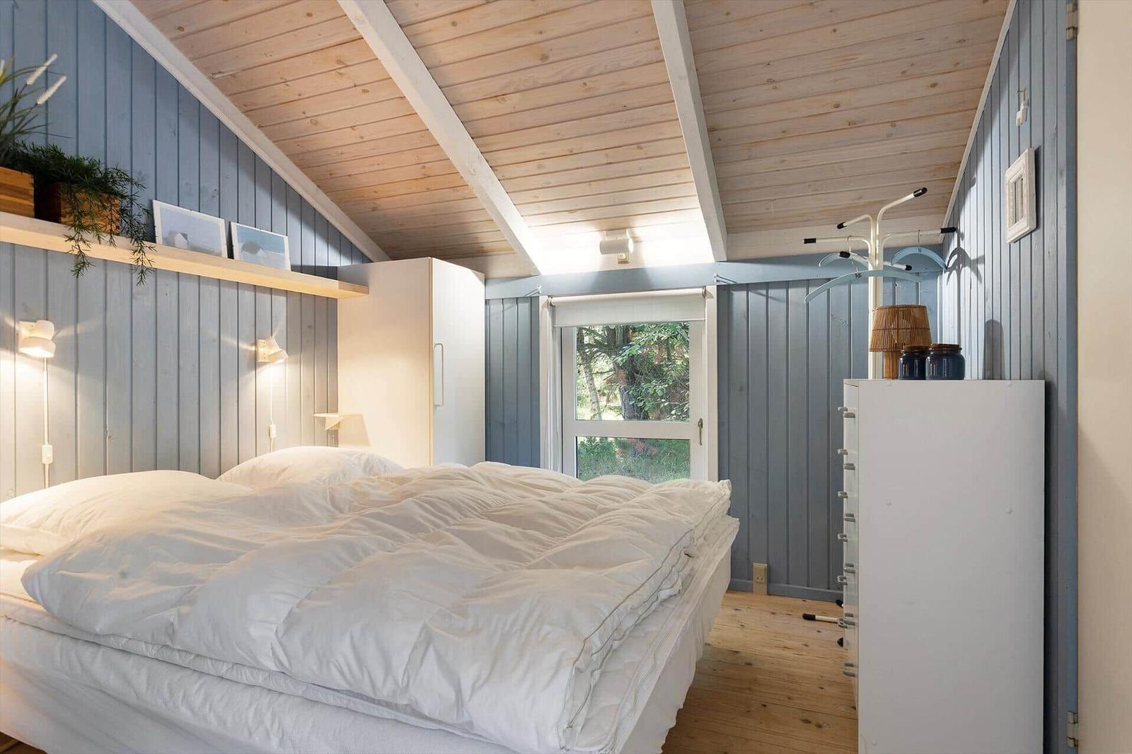 Bedroom with bed, wardrobe, and window. Wooden ceiling and blue walls.