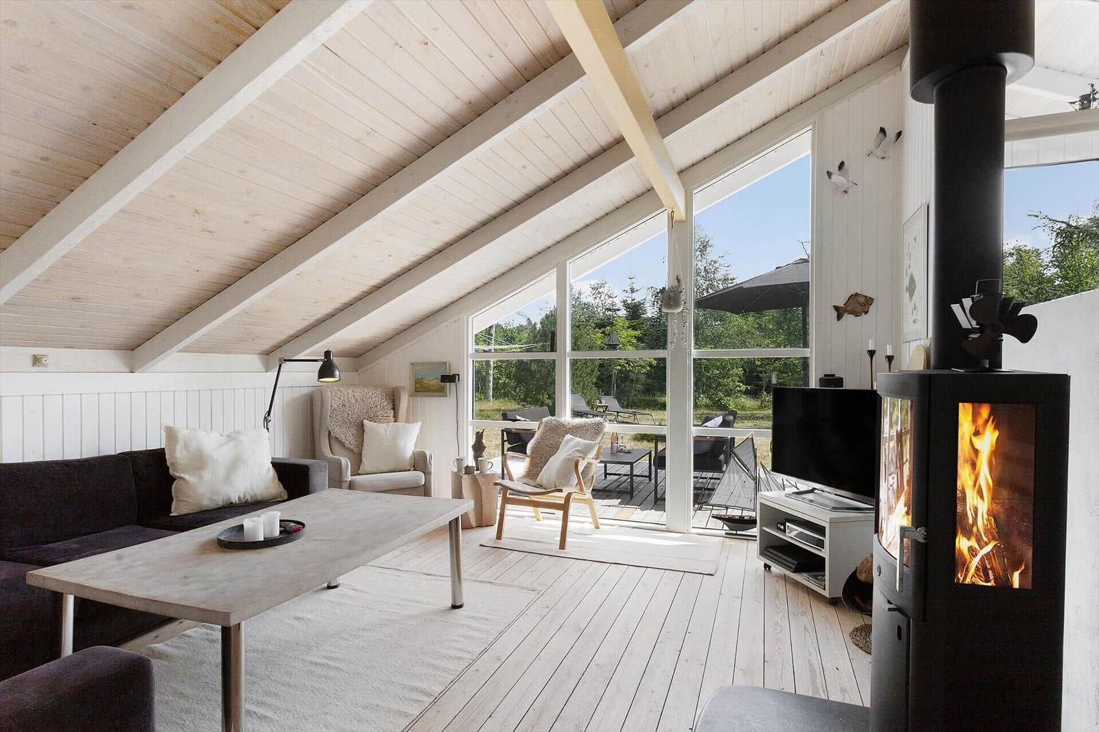 Living room with fireplace, sofa, armchairs, and large window view to terrace.