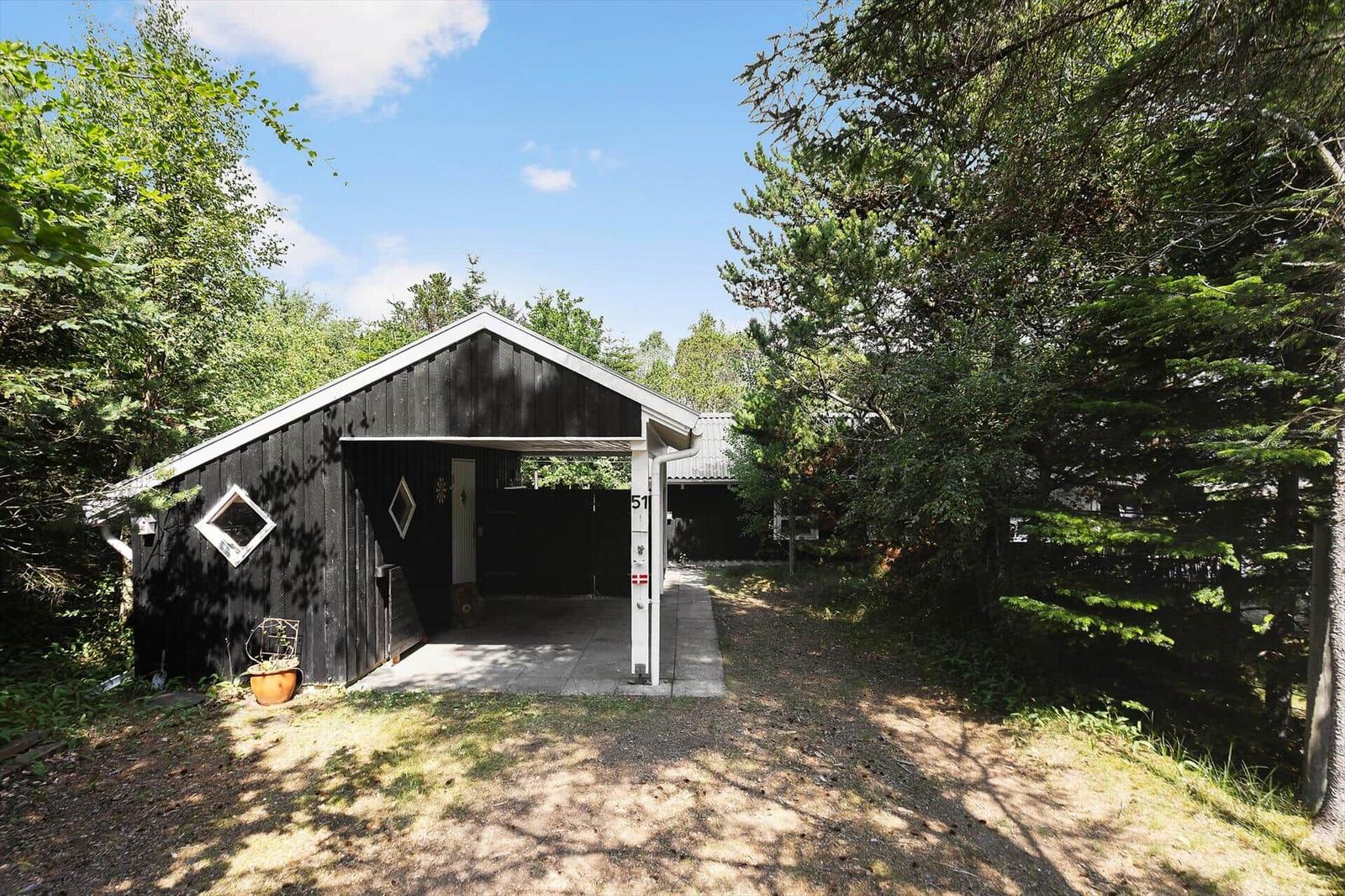 Black wooden carport with open front and plant in front
