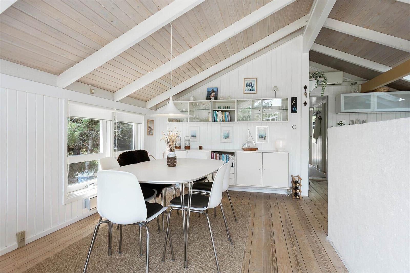 Dining area with white table, chairs, and wooden floor under a wooden ceiling
