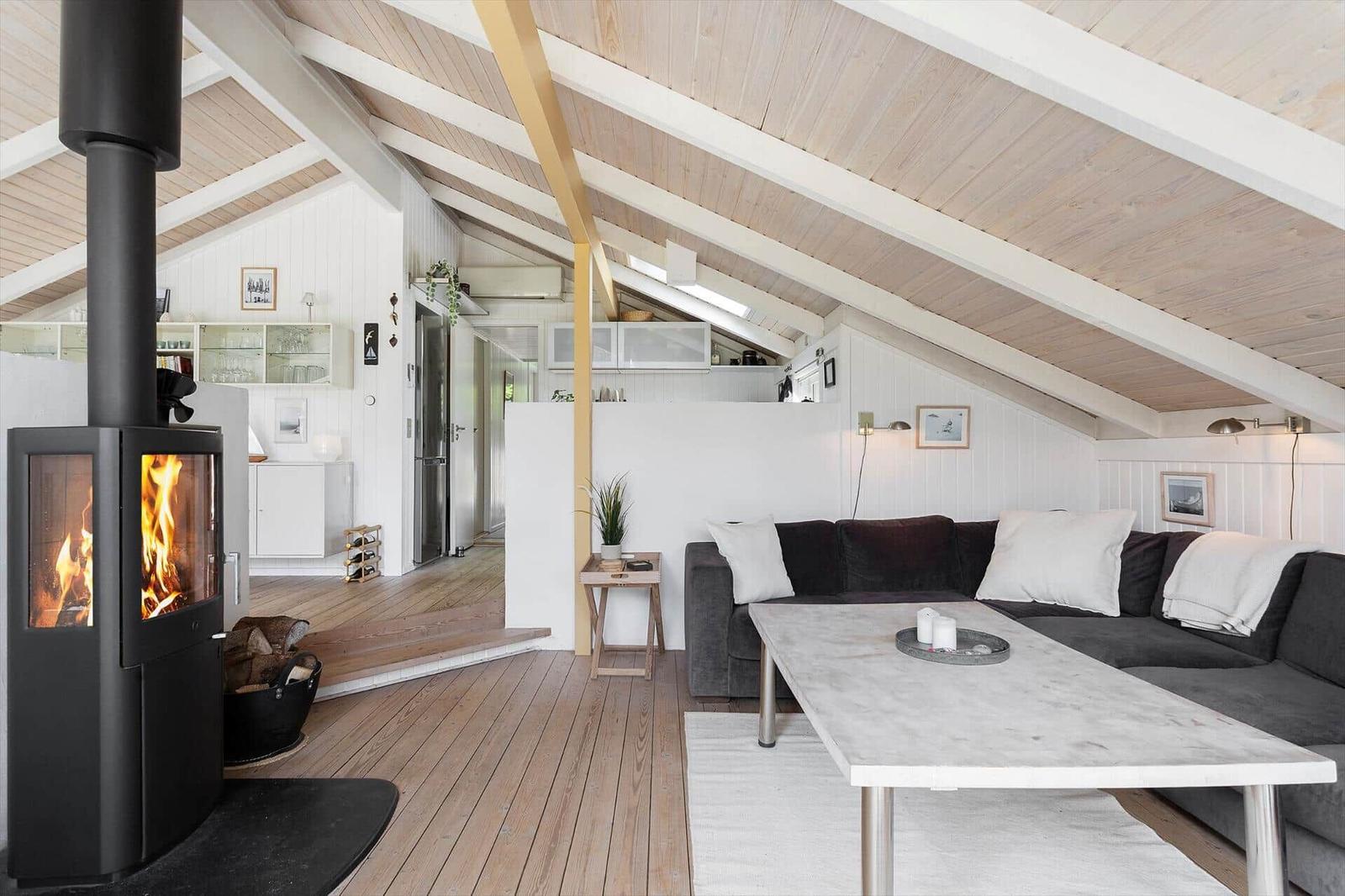 Living area with fireplace, sofa, and dining table under wooden ceiling.