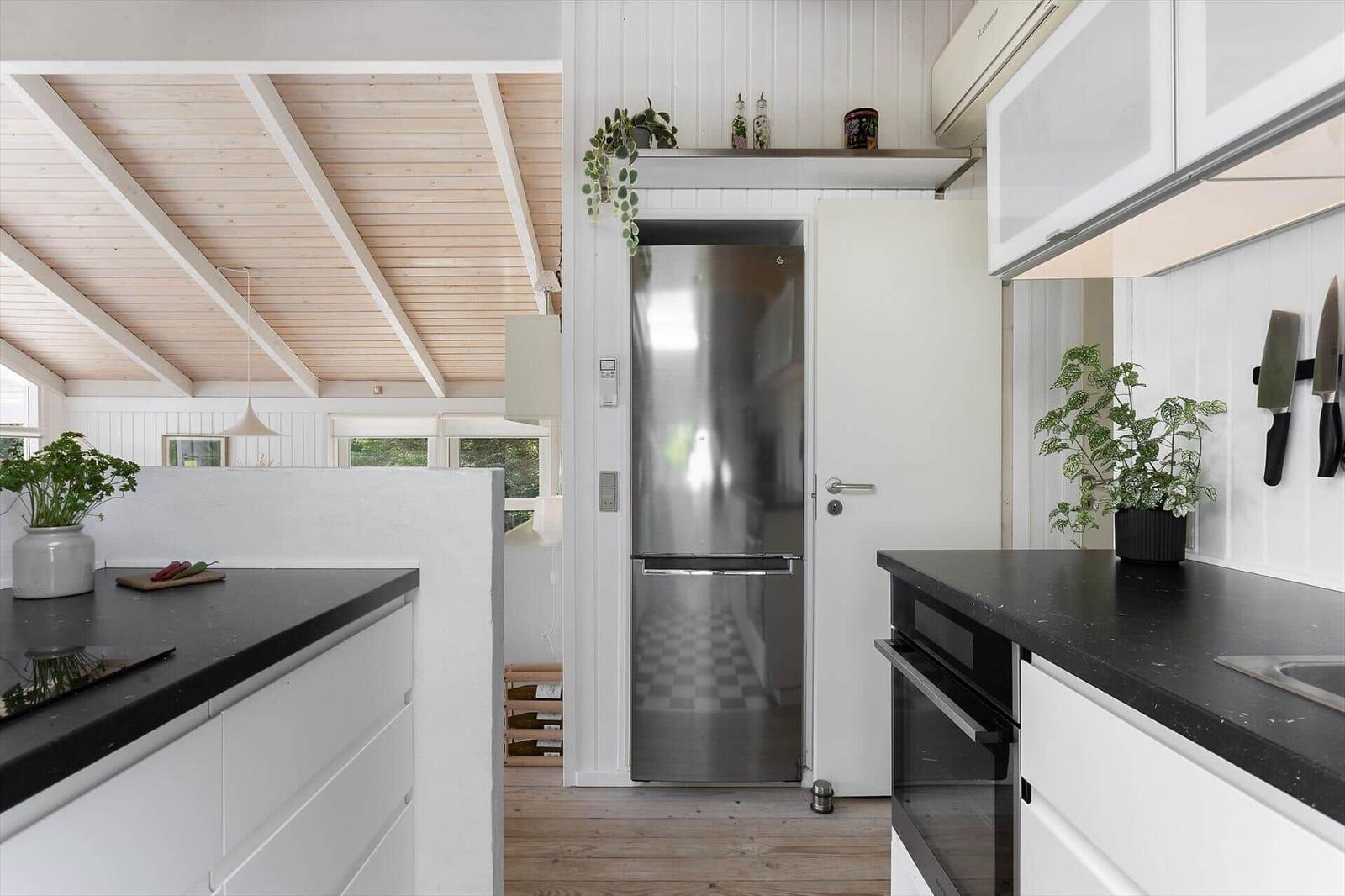Kitchen with white cabinets, black countertops, and stainless steel refrigerator.